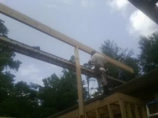 Carpenter setting a ridge beam over a new addition frame — Ice Dam Removal by Roofing Brothers in Dunn