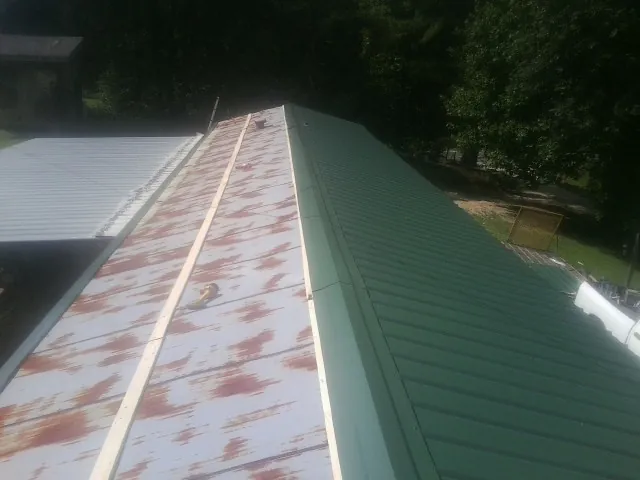 Old rusted panels beside newly installed green metal roofing — Wind Damage Roof Repair by Roofing Brothers in Dunn