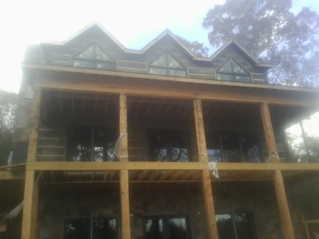 Dormers and porch framing on a large log home under construction — Roof Coating work by our crew in Dunn