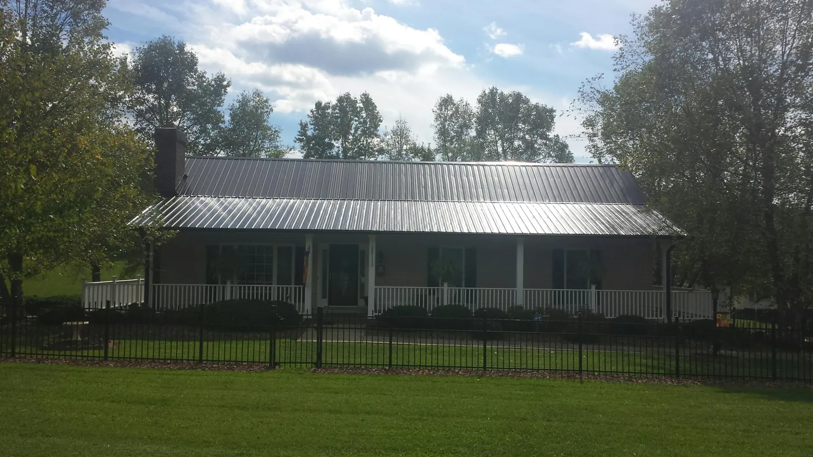 Gray metal roof on a brick ranch with a full width front porch — Gutter Guard Installation work by our crew in Dunn